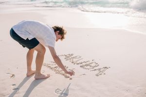 Family drawing together in the sand on a sunny beach during a tropical vacation.