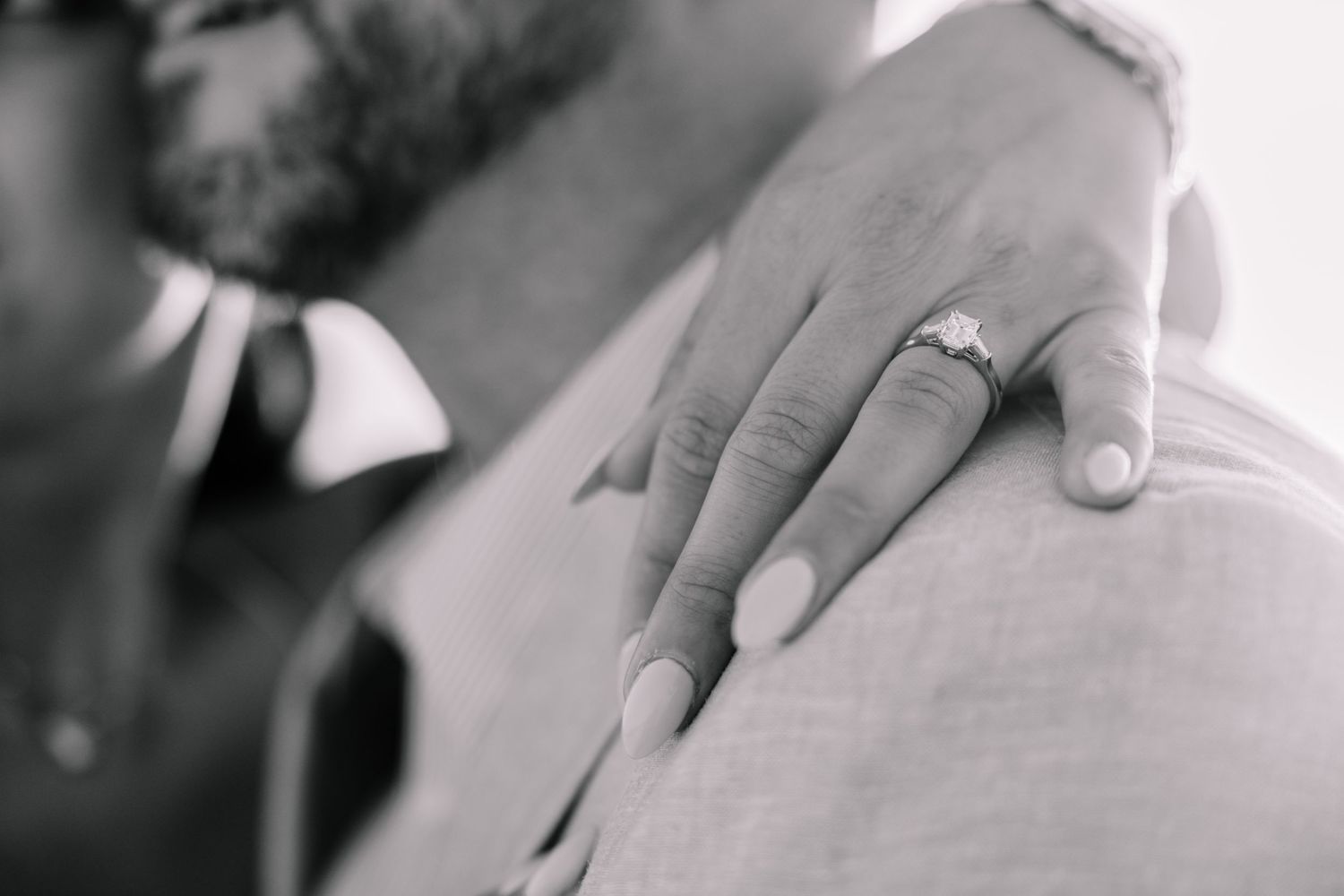 Black and white close-up of hands with engagement ring.