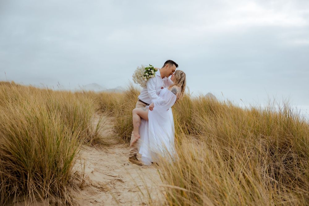 Romantic beach photoshoot with couple among coastal grass.