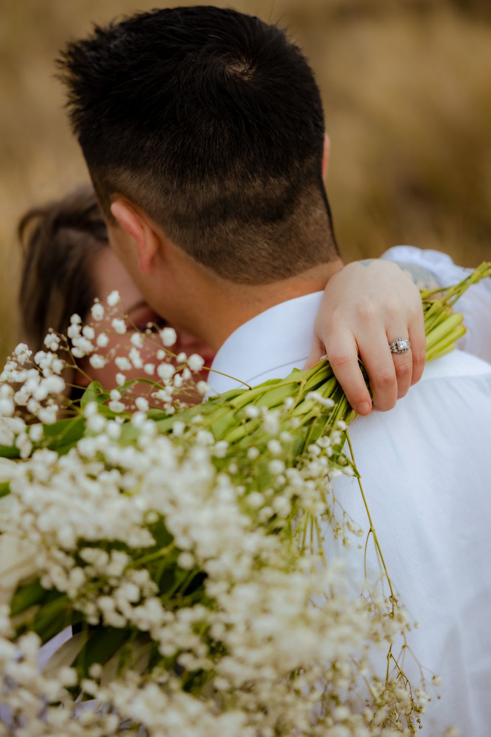 Close-up detail of white baby's breath bouquet against white shirt.