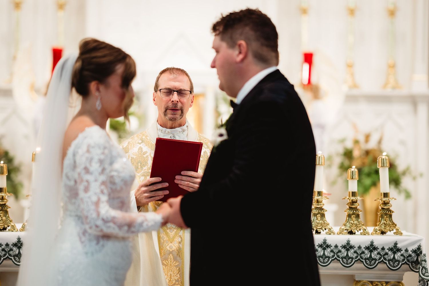A formal ceremony takes place at an elegant venue with decorative white podiums and peach-colored wallpaper.