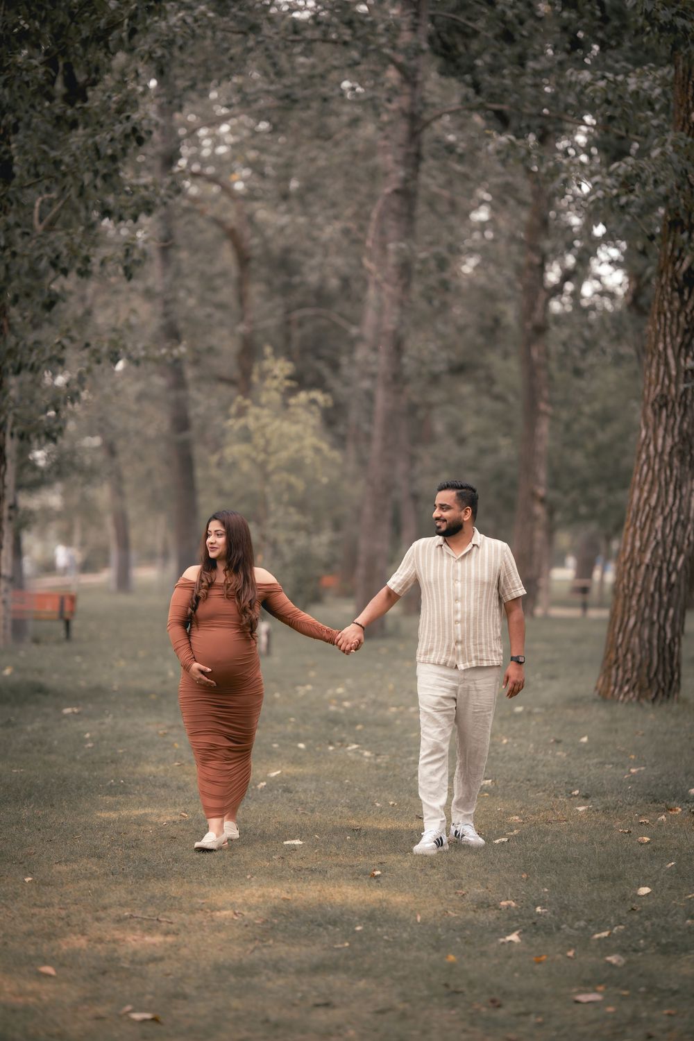 A couple in autumn outfits playfully interacting in a pine forest setting during a casual outdoor photoshoot.