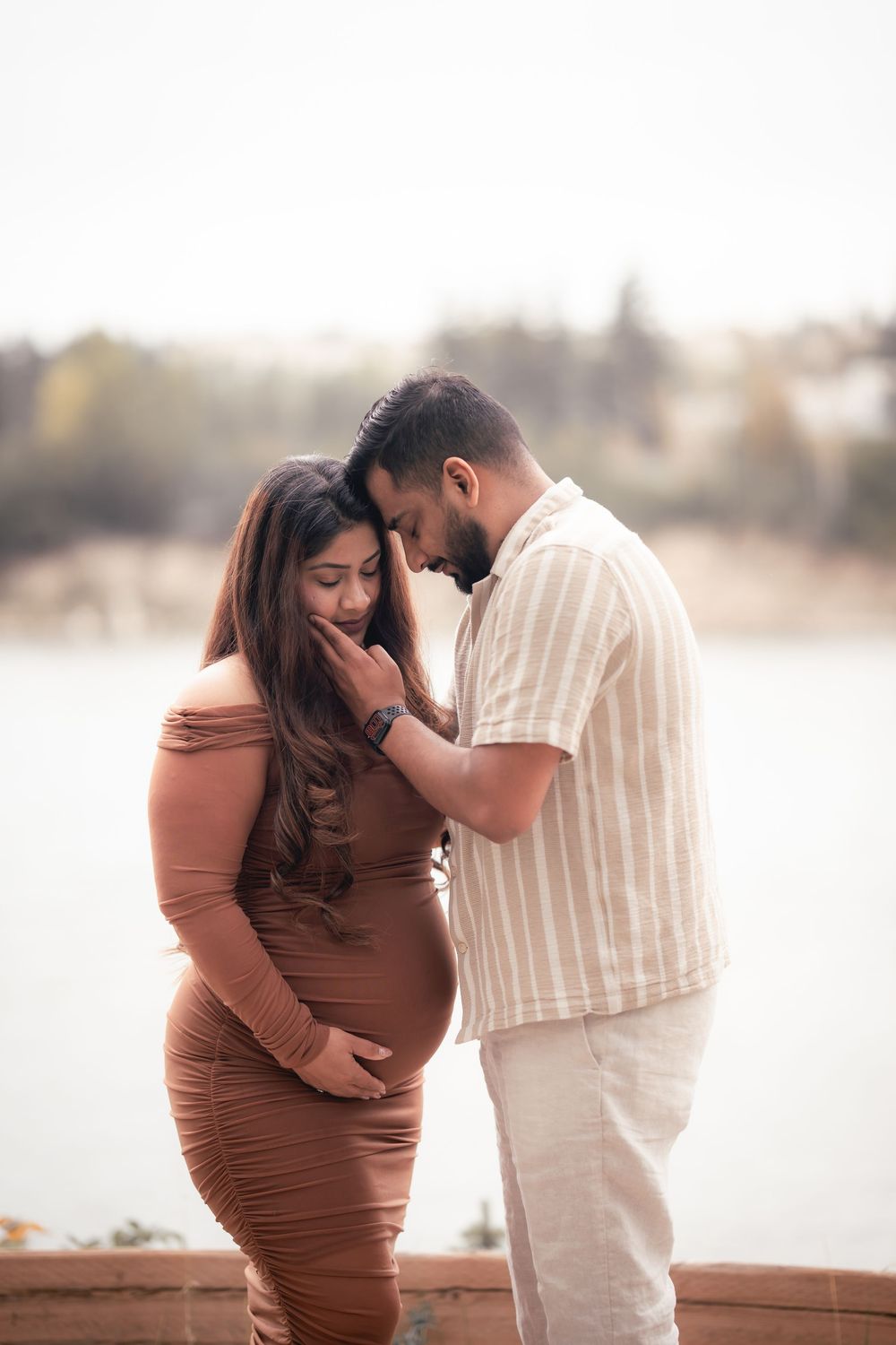 A couple shares intimate moments in a series of romantic outdoor photos wearing brown and white outfits by the water.