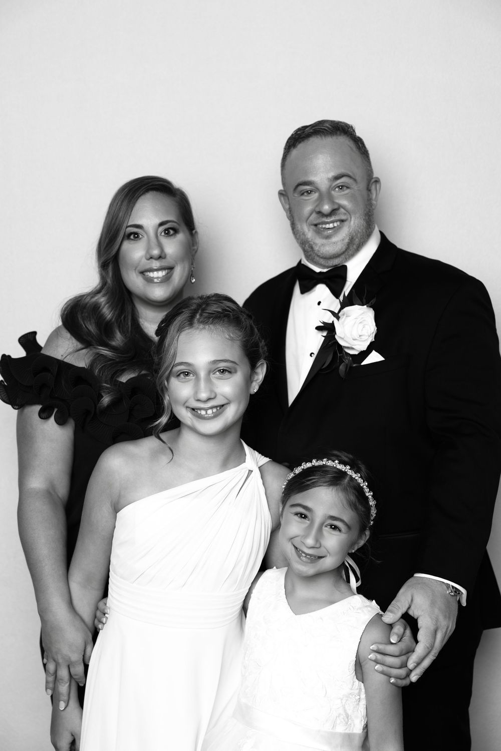 Black and white formal portrait series showing family in elegant white dresses and tuxedo.