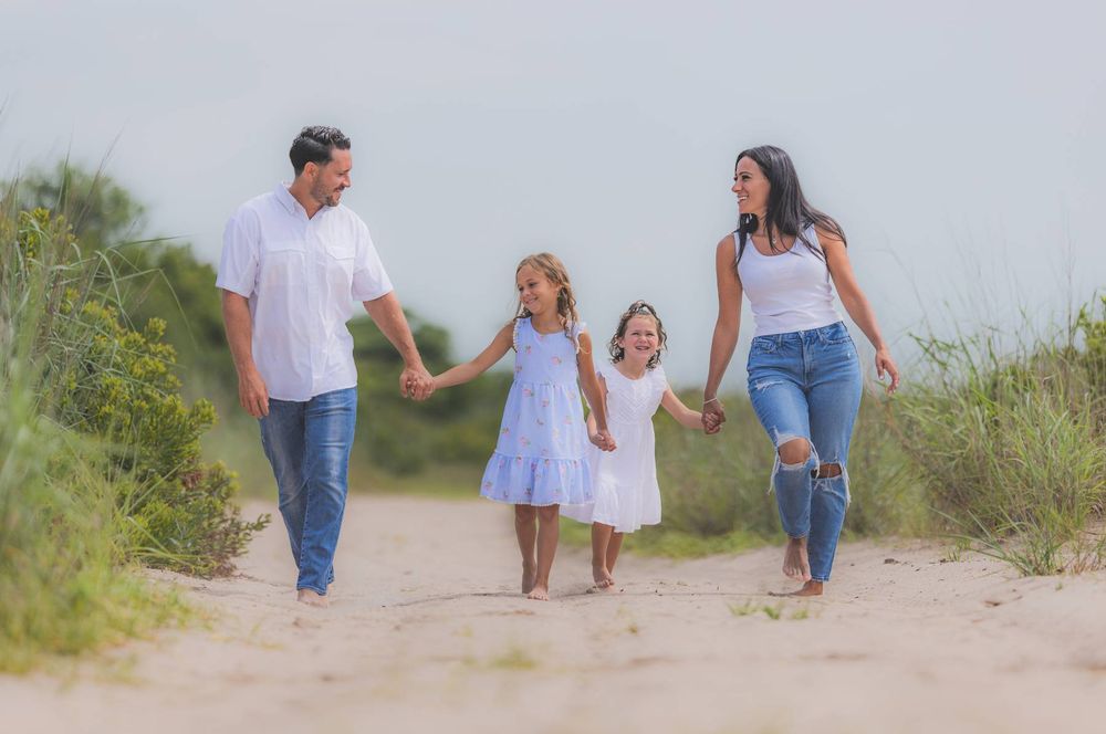 Candid family photos walking along a sandy path in coordinated white and blue outfits.