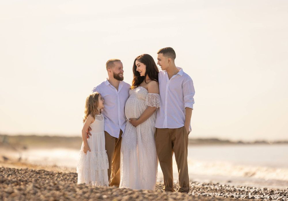 Family walking together on a beach at sunset in coordinated white and neutral outfits.