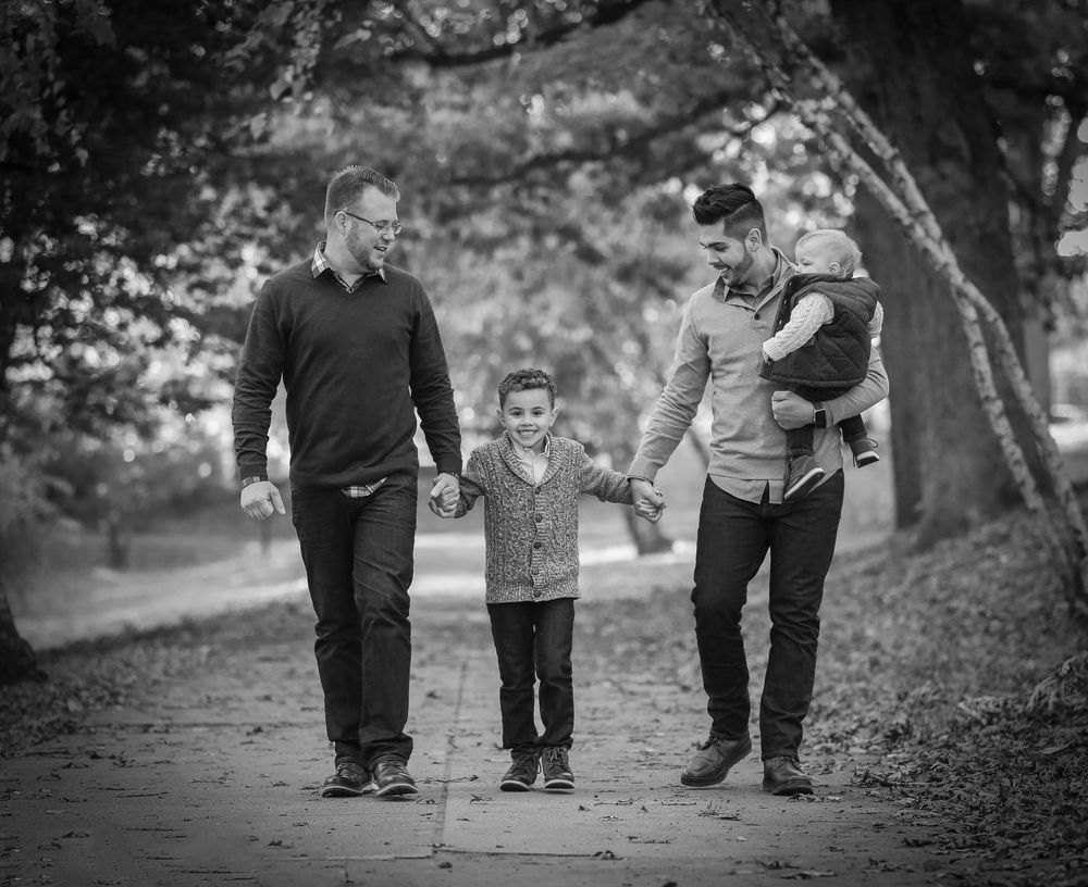 Black and white series showing family walking together on a tree-lined path.