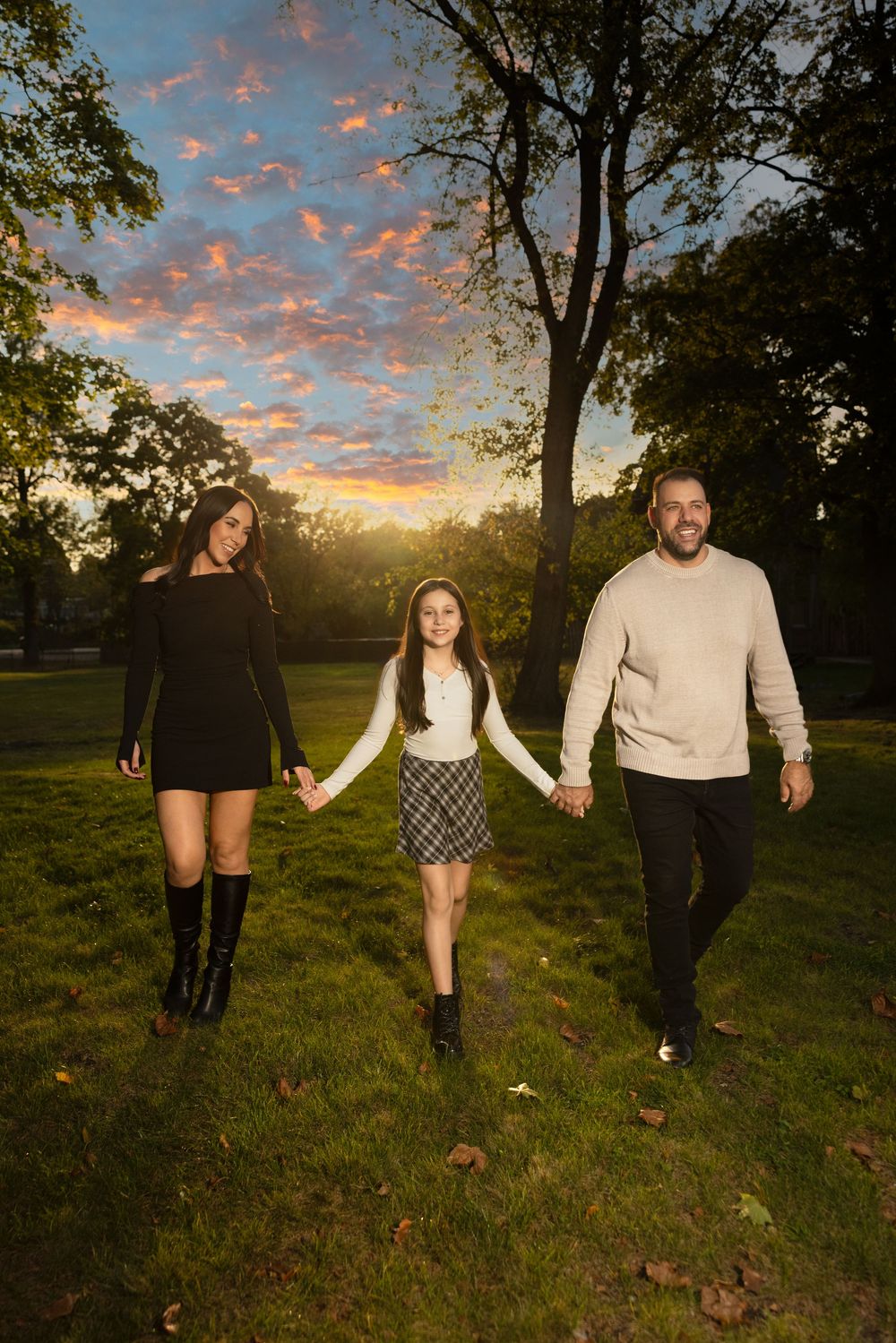 Sunset family photo session in a grassy field with dramatic orange sky.