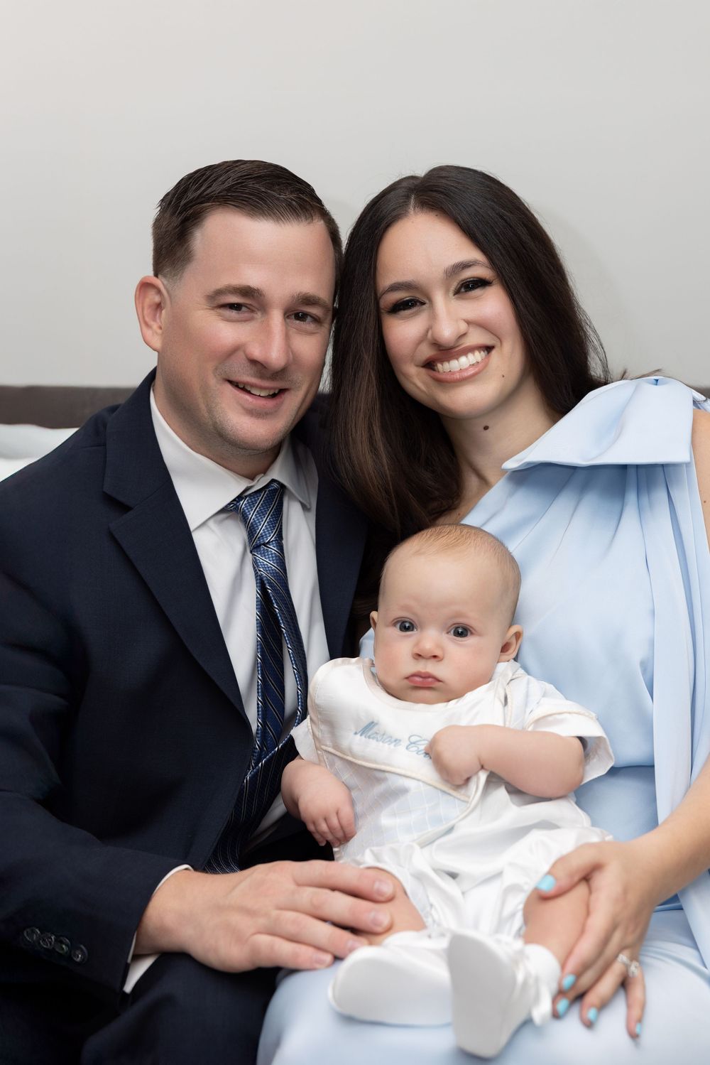 Studio portrait series showing tender family moments with an infant in white clothing.