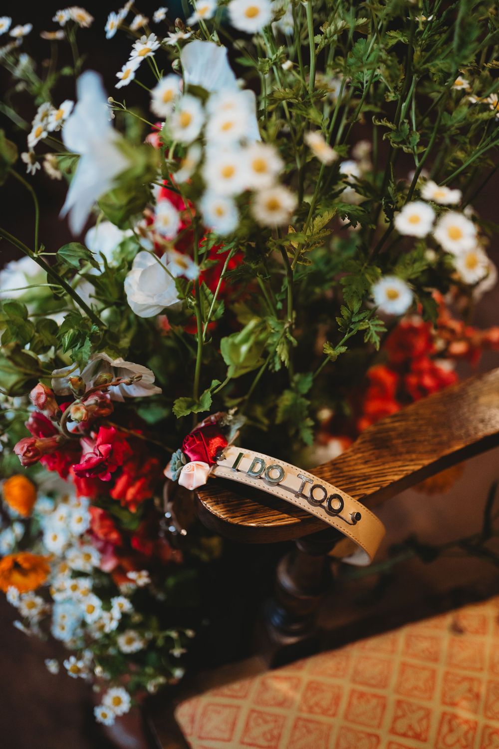 Delicate white daisies and red flowers arranged with a vintage wooden tag reading 'the 100s'.