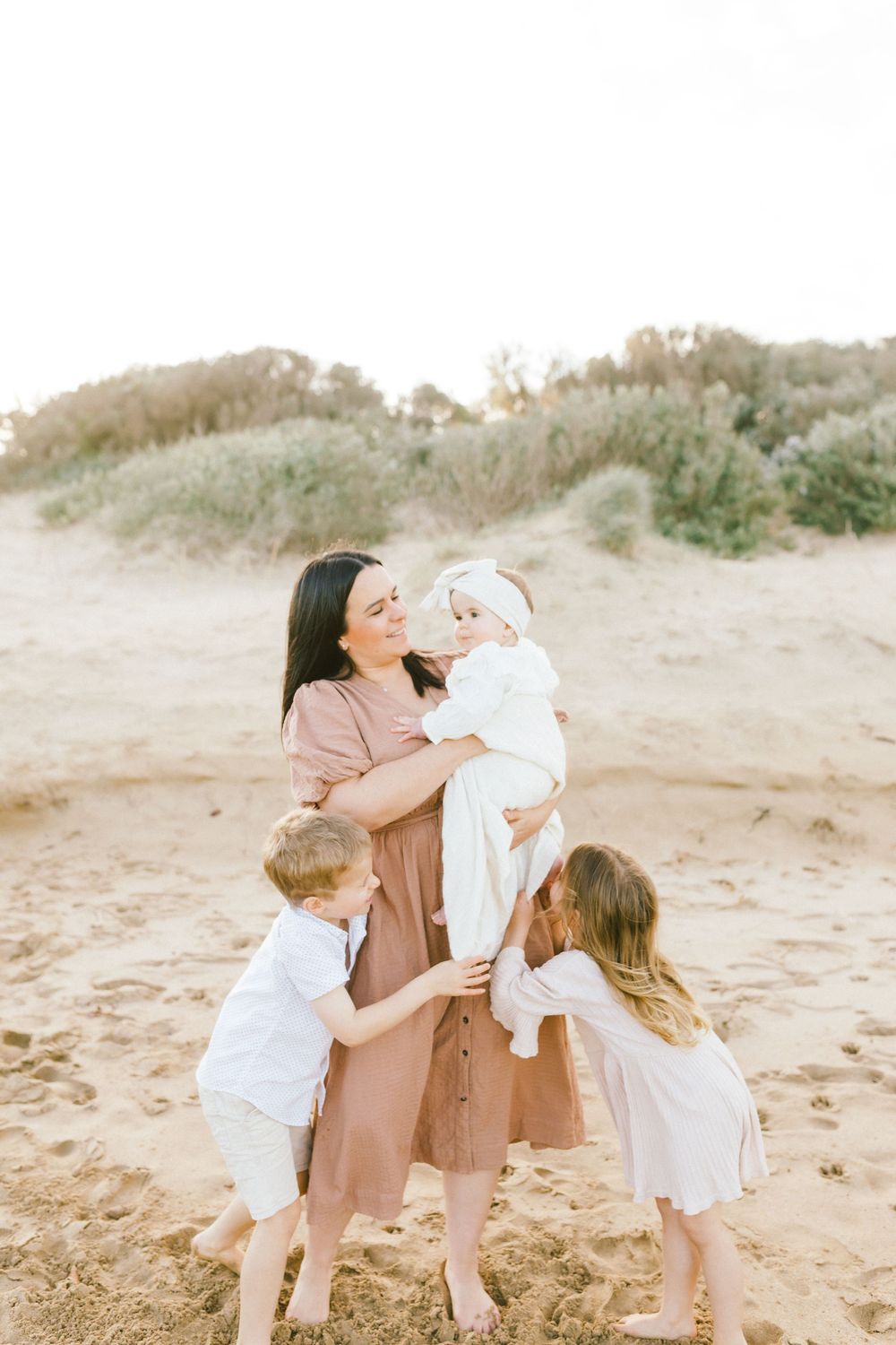 A family shares joyful moments together on a sandy beach during golden hour.