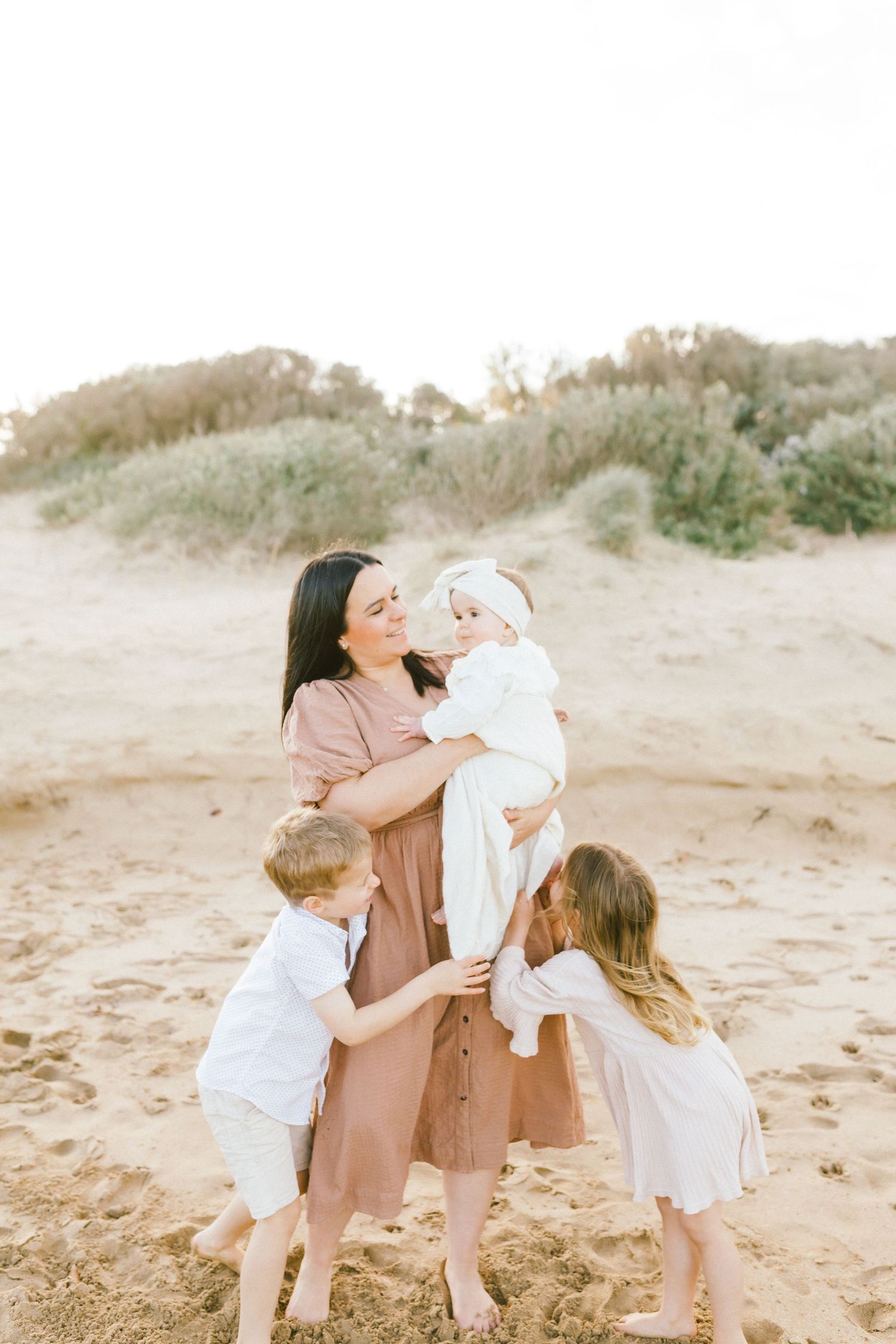 A family shares joyful moments together on a sandy beach during golden hour.