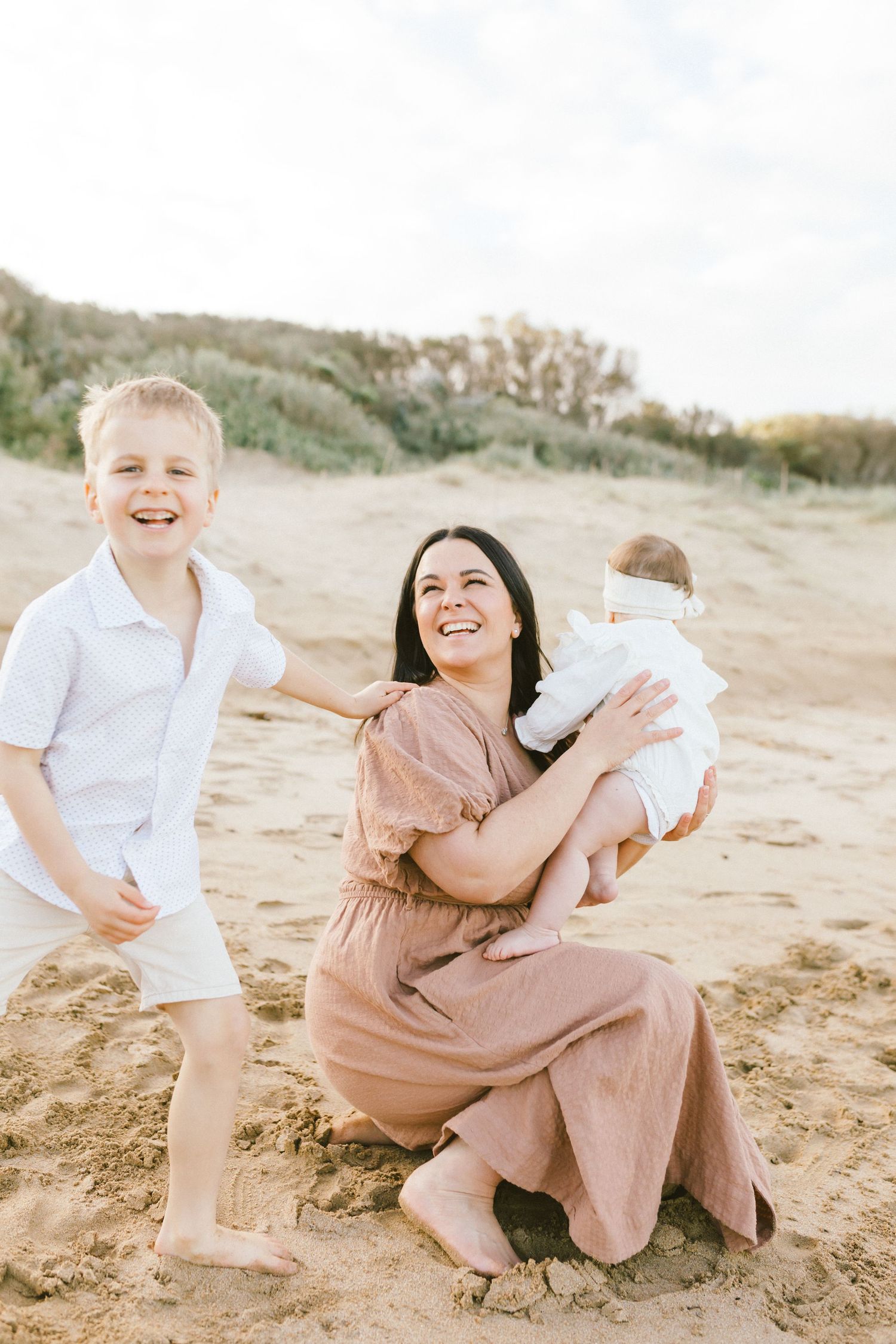 A joyful family moment captured on a sandy beach with natural coastal scenery in the background.