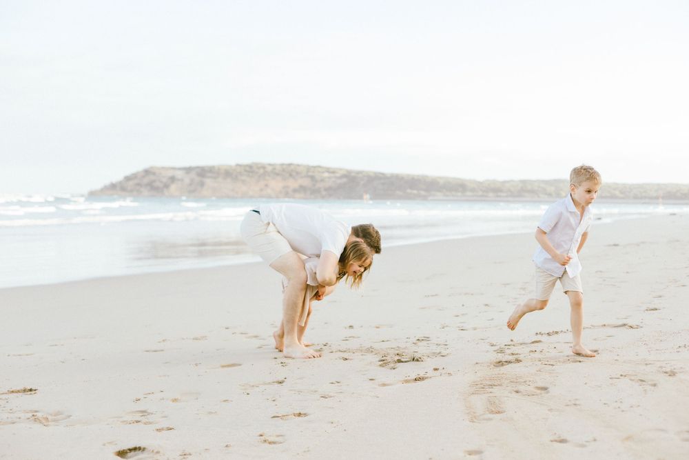 A golden retriever runs and plays fetch with someone on a sunny beach during golden hour.