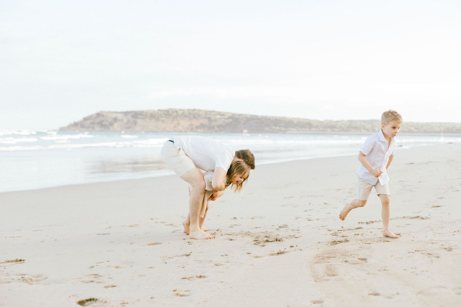 A golden retriever runs and plays fetch with someone on a sunny beach during golden hour.