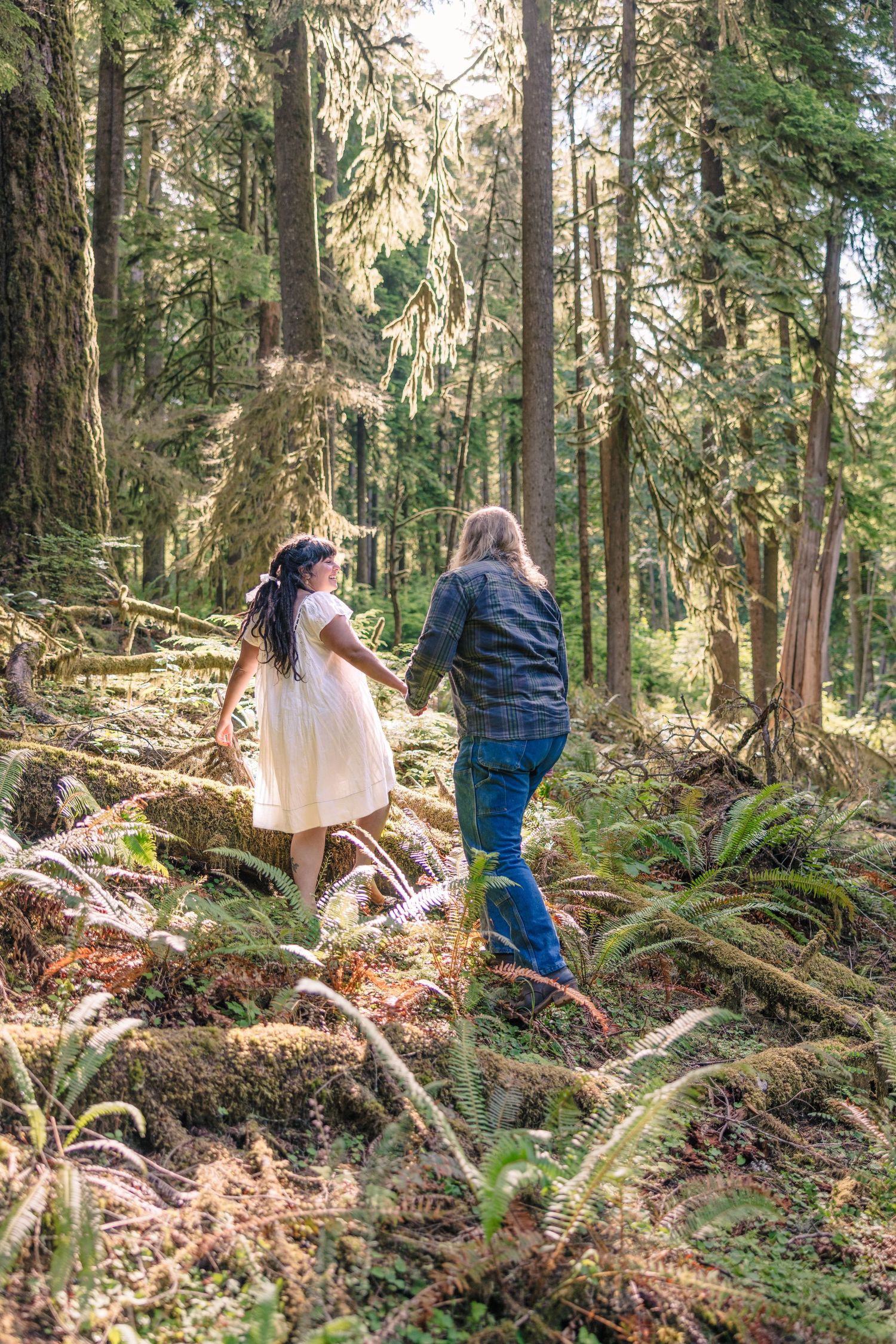 People walking through a lush forest path with sunlight filtering through trees.