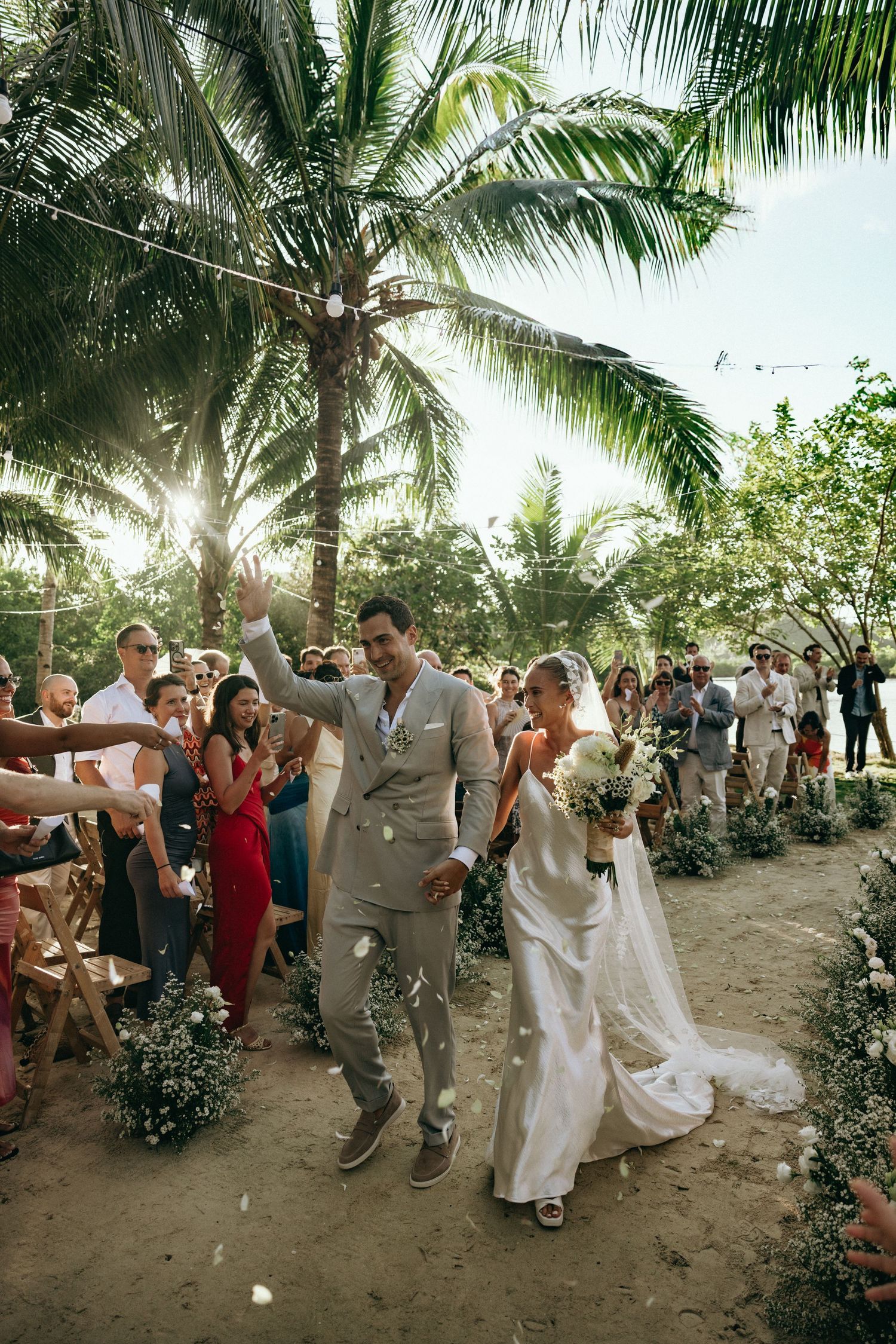 Joyful wedding celebration with guests dancing under palm trees.