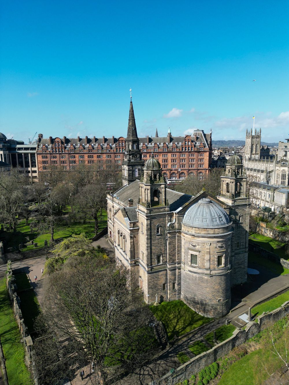 Historic Edinburgh buildings and castle architecture shown in panoramic view against blue sky.