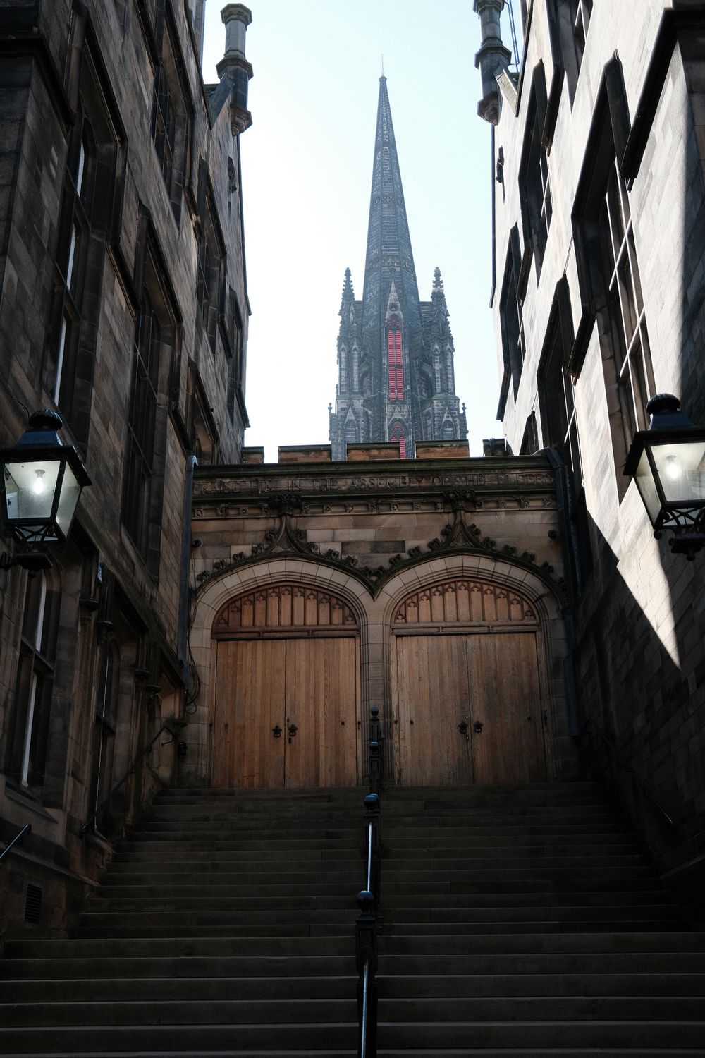 Gothic cathedral spires rise above stone steps leading up a narrow medieval street in Edinburgh's historic Old Town.