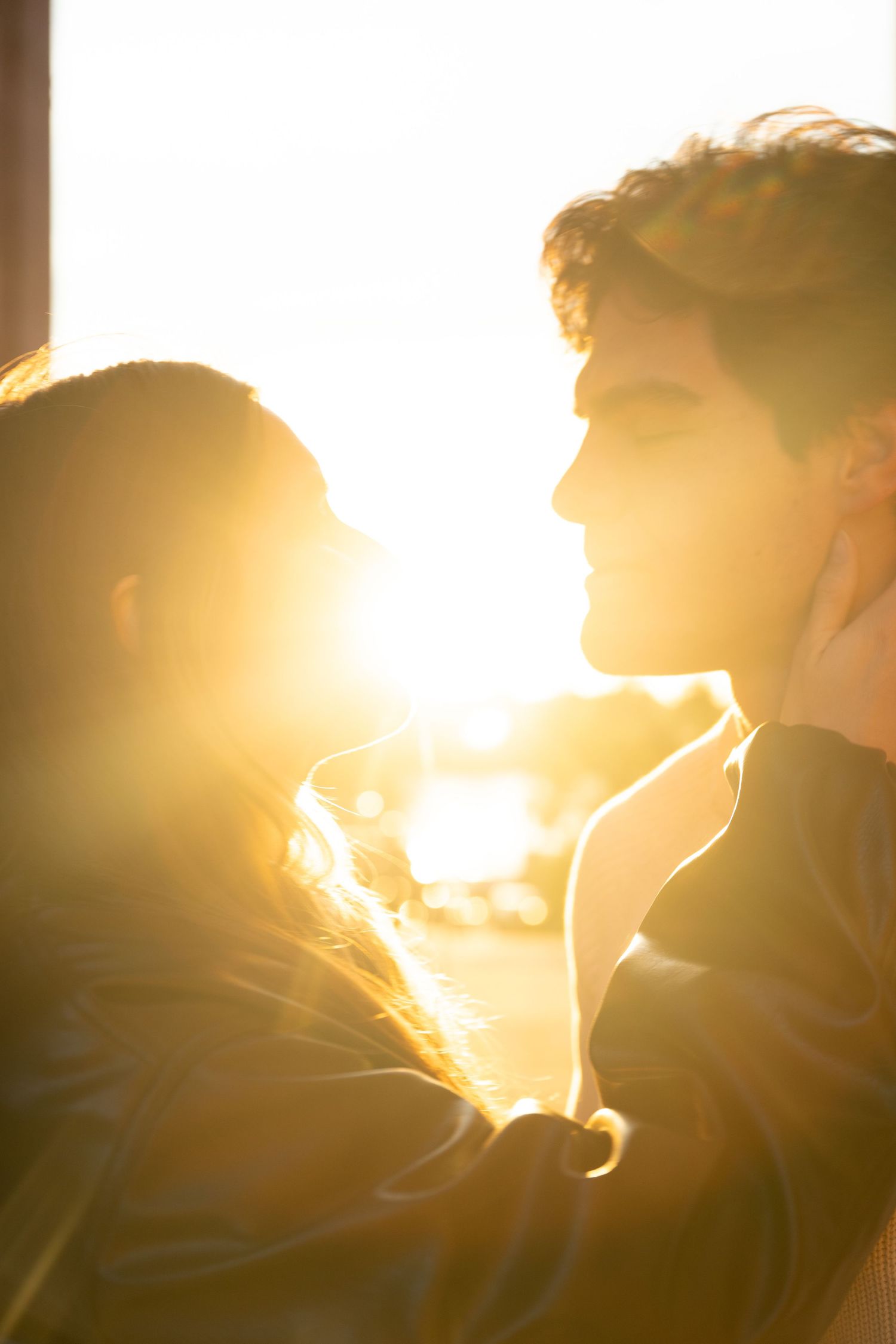 Silhouetted figures in a romantic embrace against a glowing golden sunset background.