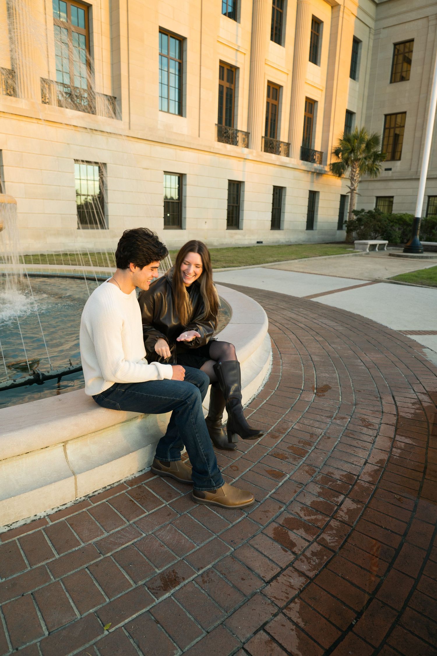 Two students sit and study together on curved stone steps outside a grand academic building with arched windows.