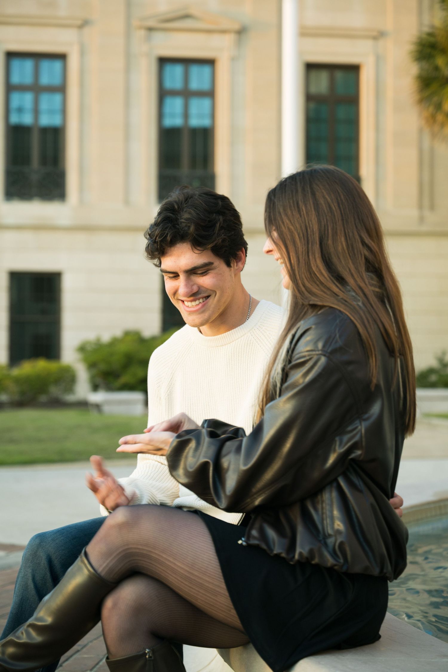 Students review notes and study materials while sitting on outdoor stone steps of a university building.