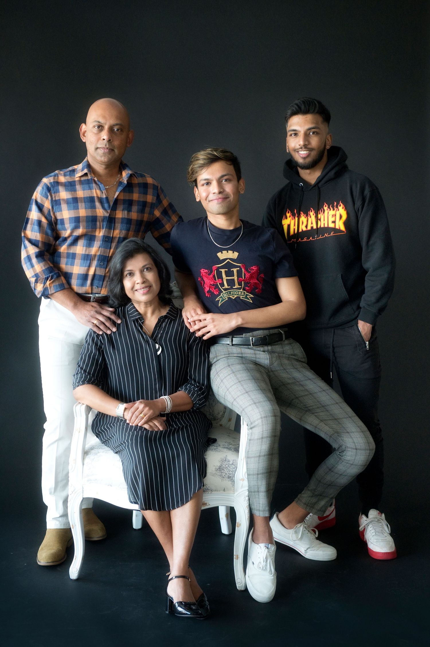 Studio portrait of four family members in casual attire against dark background.