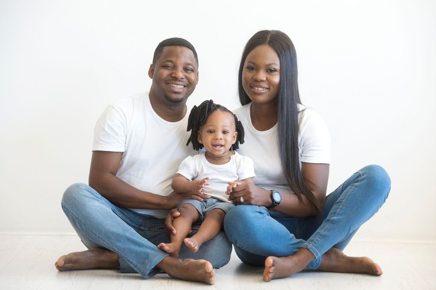 Family portrait of three in matching white t-shirts sitting on white background.