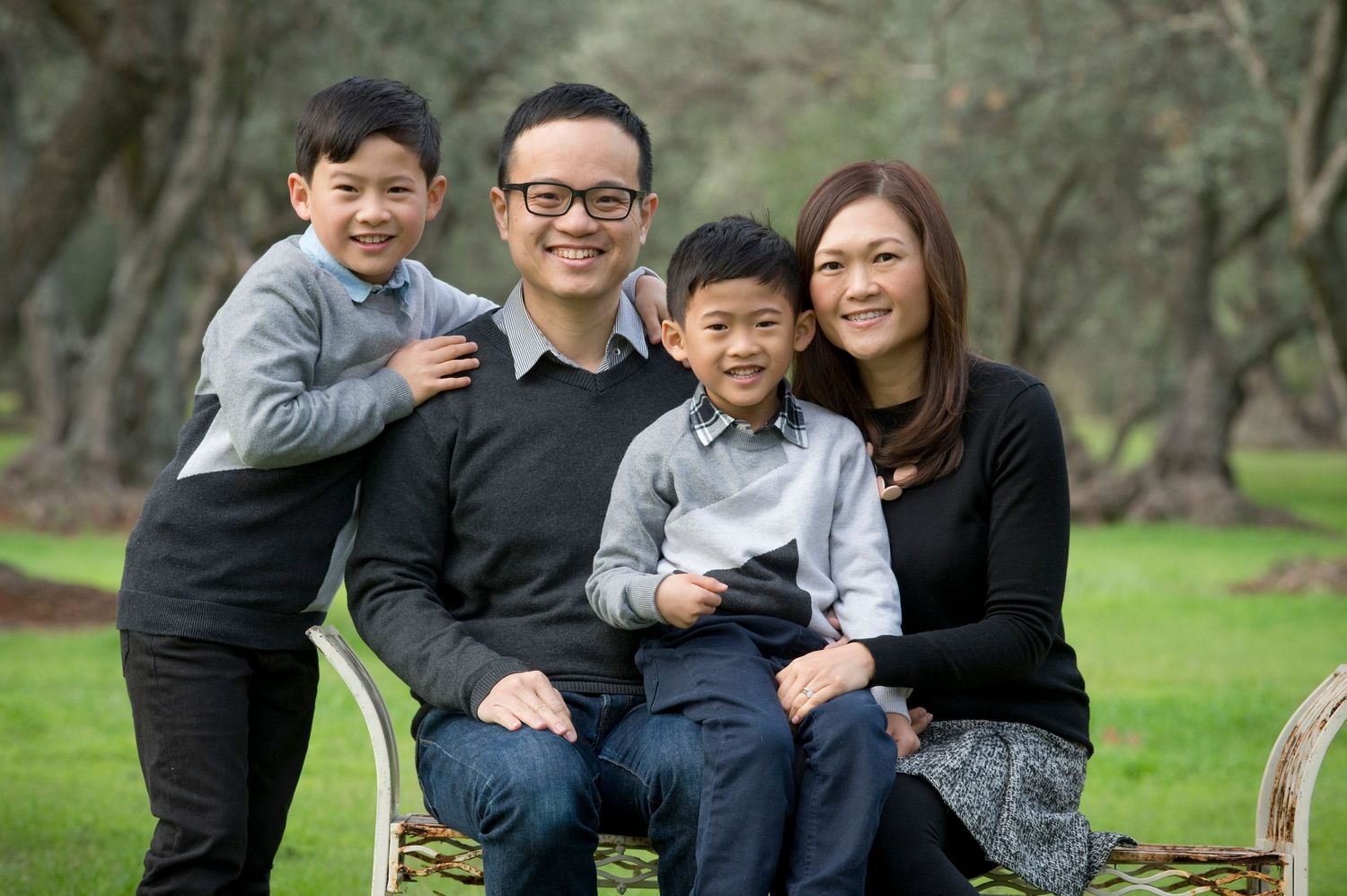 A casual outdoor family photo session showing playful interactions in a natural wooded setting.