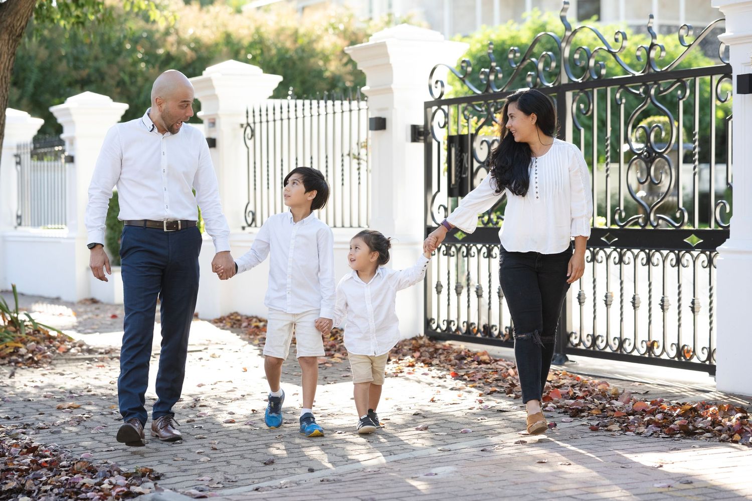 Family portraits taken along ornate iron gate and garden path.