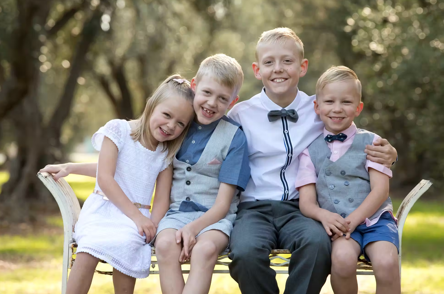 Candid family portrait of group sitting together on wooden bench outdoors.