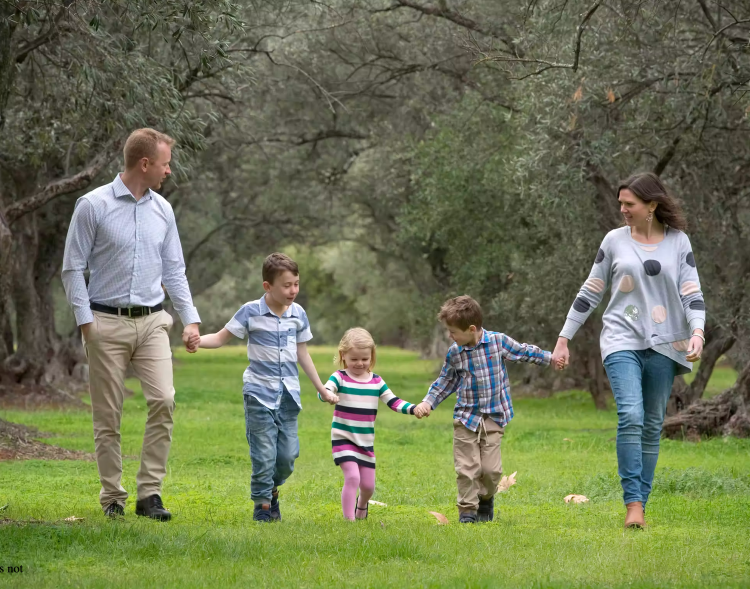 Children playing and running through a grassy field during outdoor photo session.