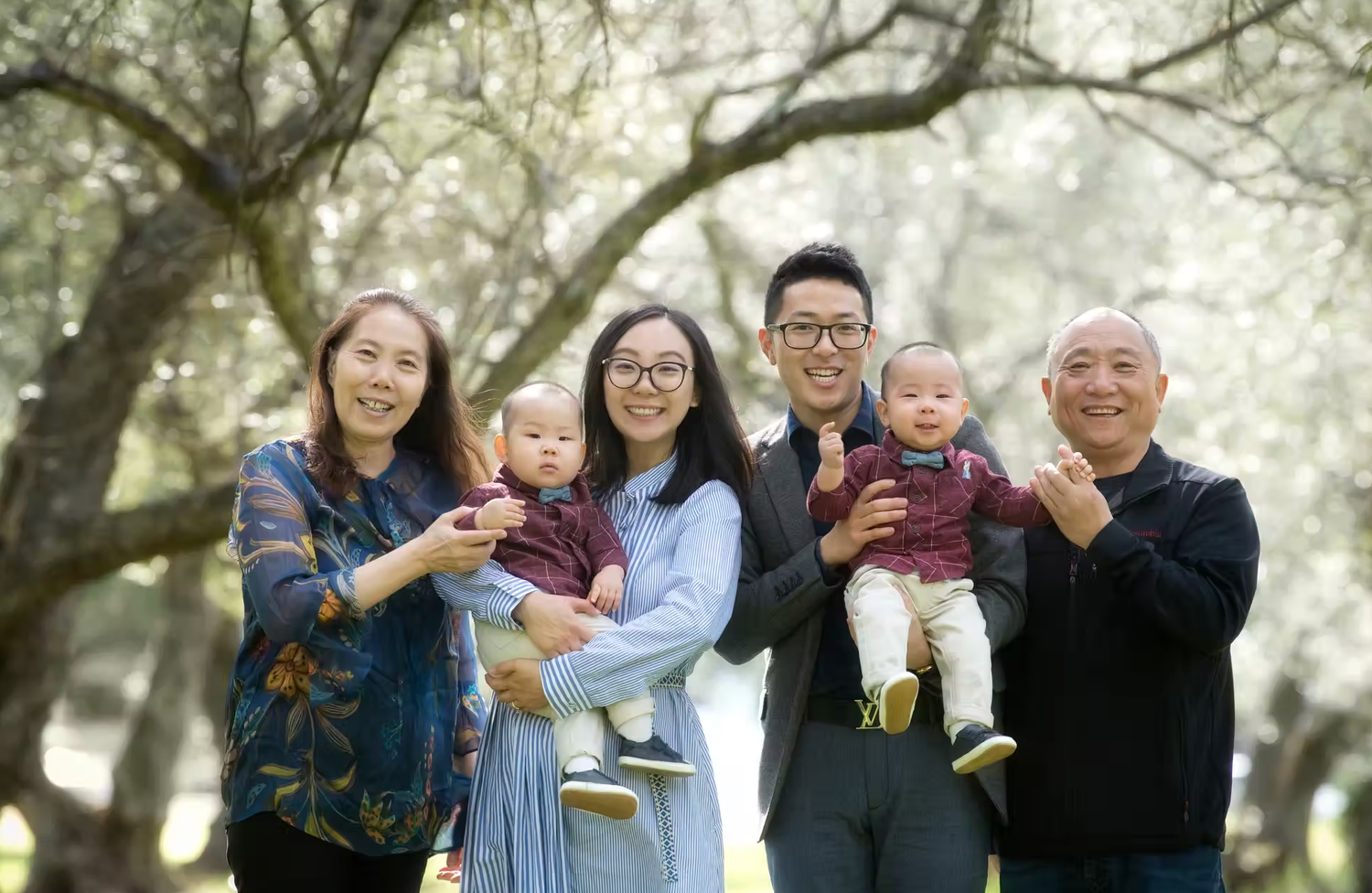 Family group photos taken under blooming spring trees with soft natural lighting.