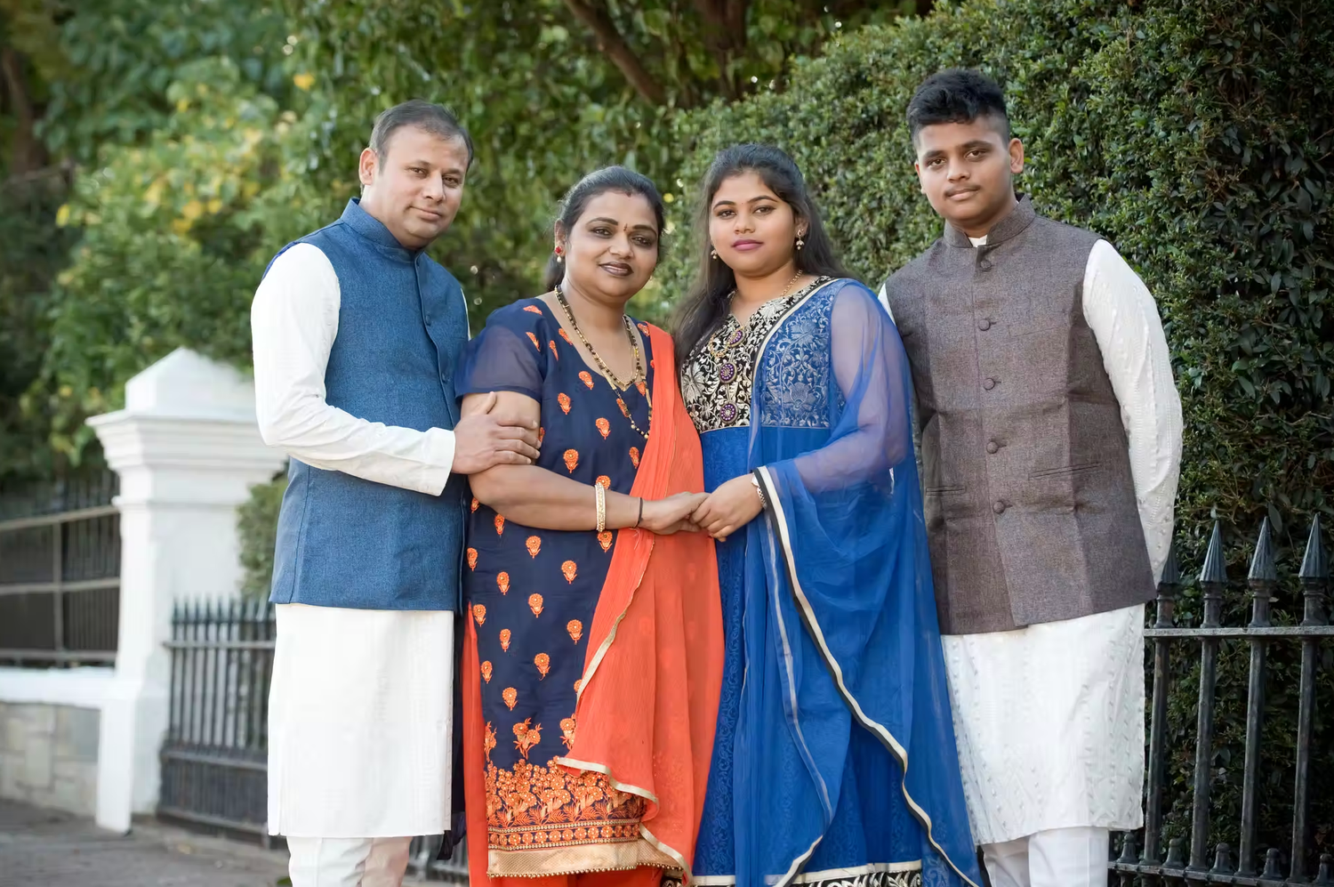 Family group portrait in traditional ethnic attire with coordinated blue and orange colors.