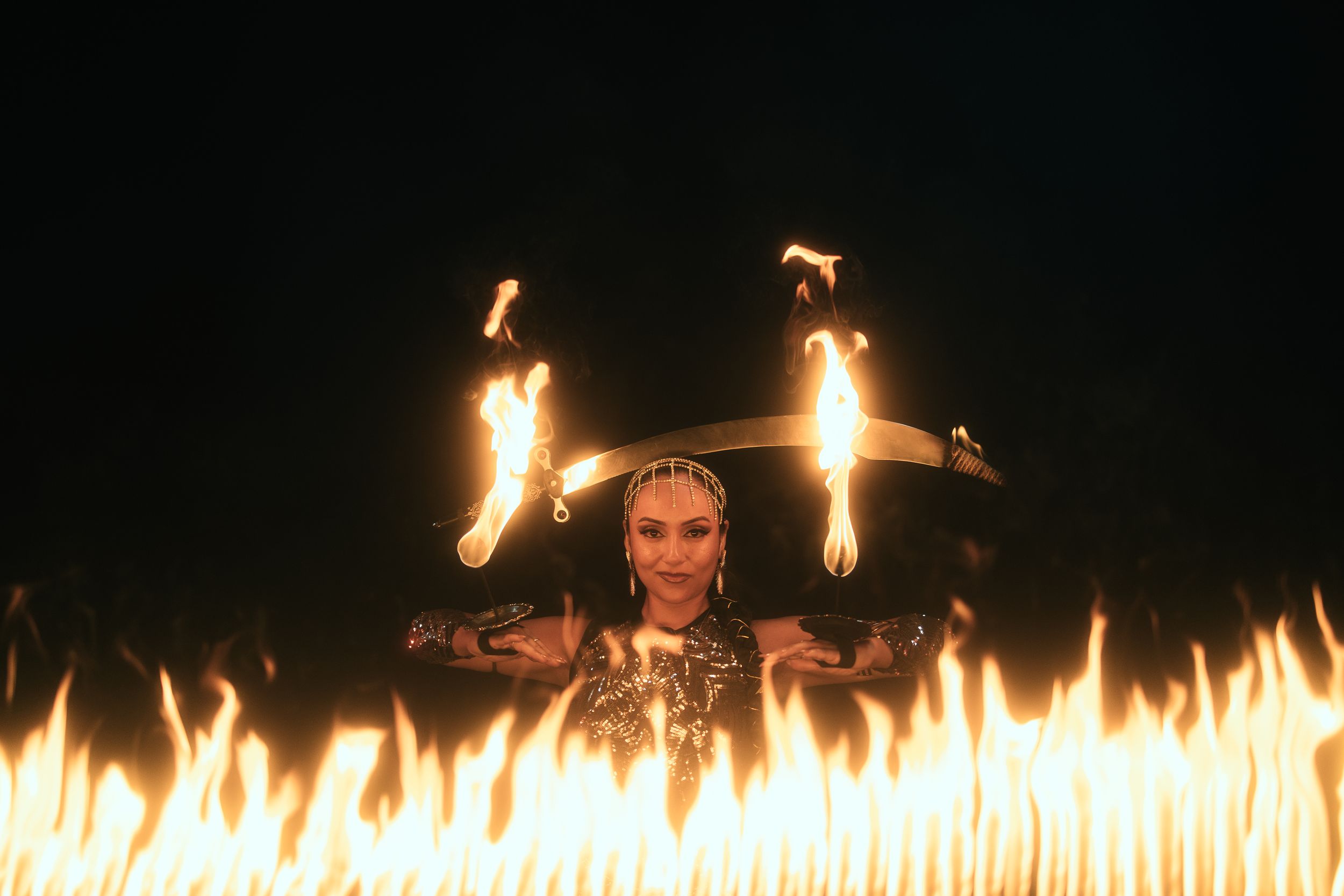 West Palm Beach fire dancer captured by Mannyportraits. Performer raising arms behind a line of flames in cinematic and powerful composition