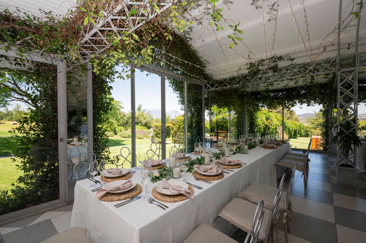 A series of modern interior spaces with glass walls and lush greenery growing along the ceiling and walls creates a natural ambiance.