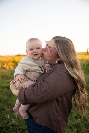 Parent and baby share joyful moments together in a field at sunset, captured in a series of candid photos.