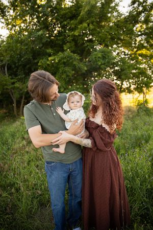 A family shares tender moments together in a grassy field at sunset, captured in a series of connected photos.