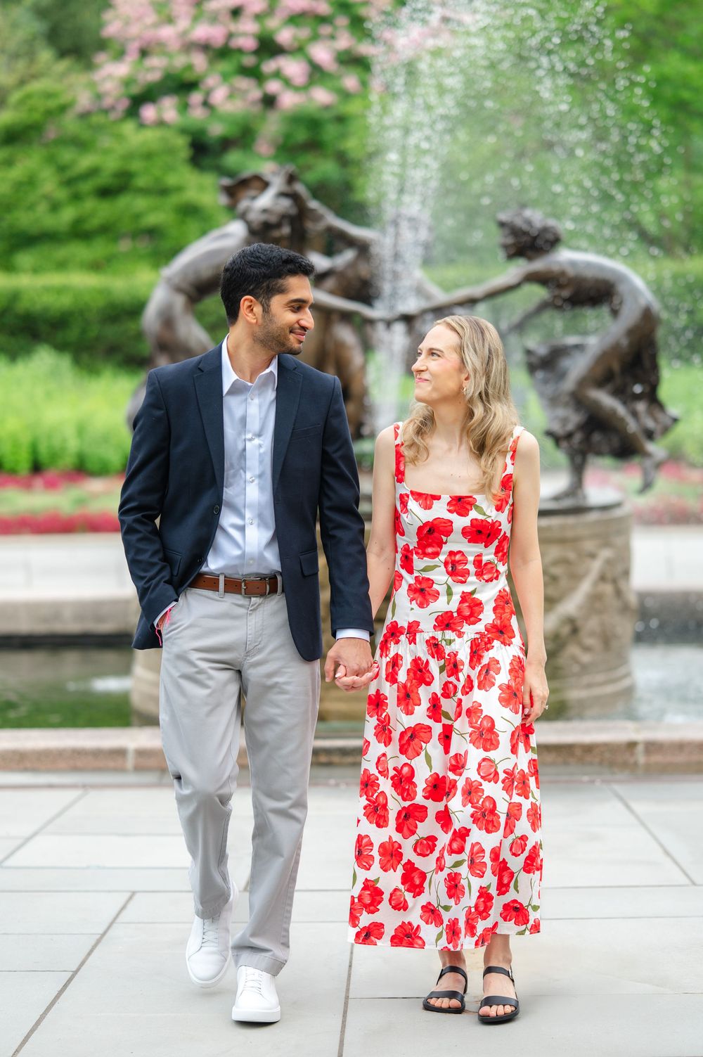 A couple in coordinated outfits walking together in Central Park Conservatory Garden during a proposal session captured by NYC photographer.
