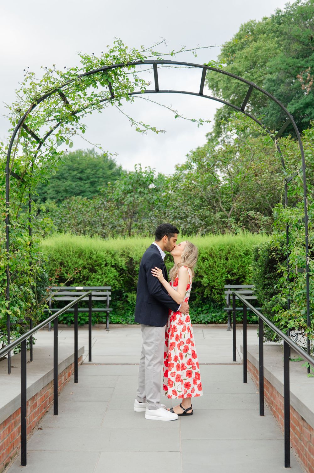 A romantic scene under a garden archway with beautiful landscaping.