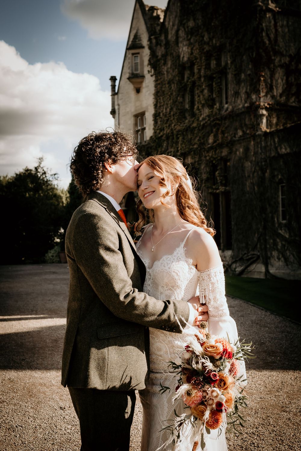 Romantic wedding portraits with warm lighting showing a couple embracing against a gothic stone building backdrop.