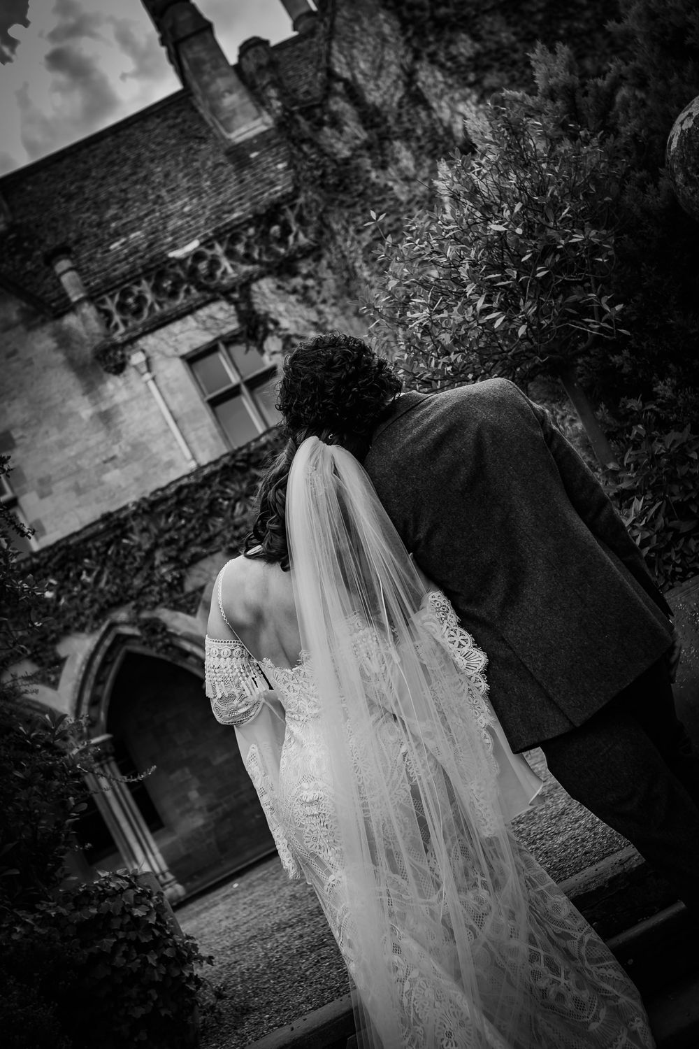 Artistic black and white wedding photography showcasing a flowing dress and veil against architectural details.