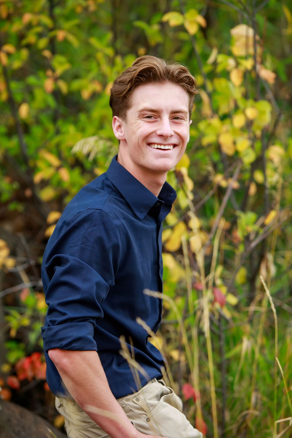 A series of outdoor portrait shots against autumn foliage wearing a navy blue shirt.