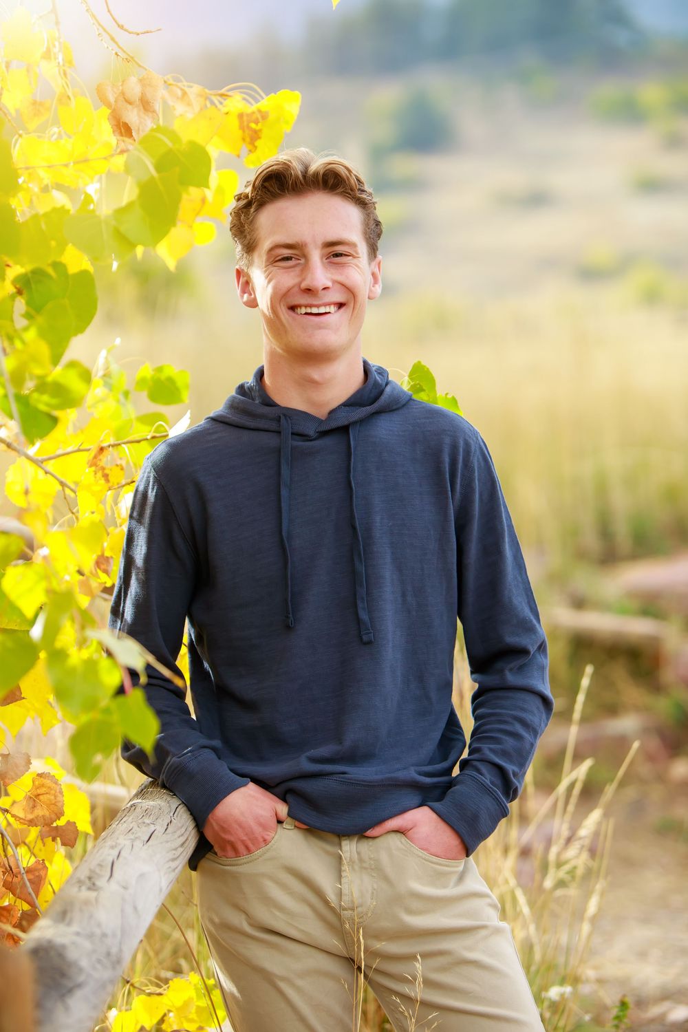 Casual outdoor portrait series in navy hoodie against vibrant yellow autumn foliage background.