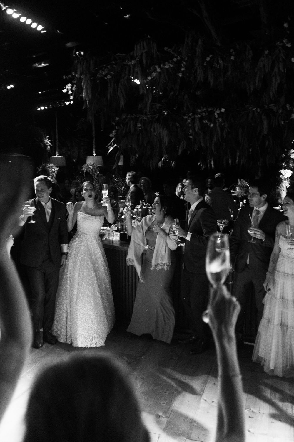 Black and white photo of couples dancing at an elegant wedding reception with formal attire and gowns.