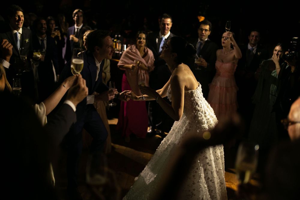 A couple shares a romantic dance at their wedding reception while guests look on in a dimly lit venue.