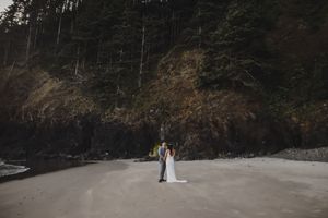 A couple stands together on a scenic forest path during their intimate outdoor wedding ceremony.