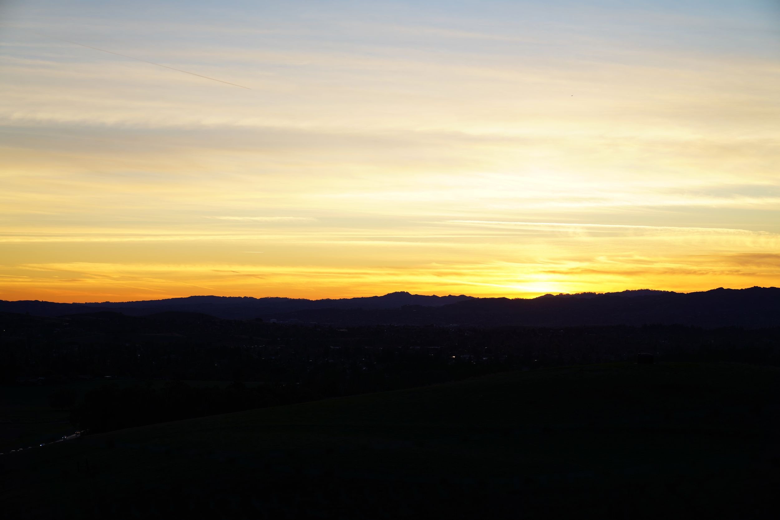 Silhouetted mountain range against a darkening sky creates a dramatic dusk landscape.