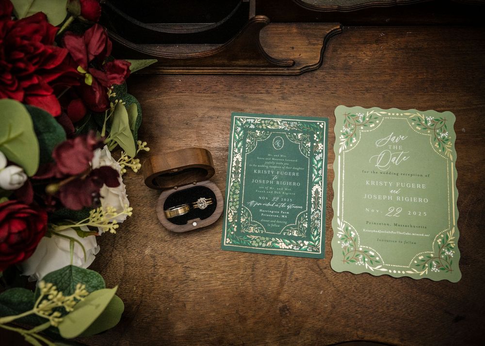 Vintage wedding invitations with decorative borders displayed on dark wooden surface.