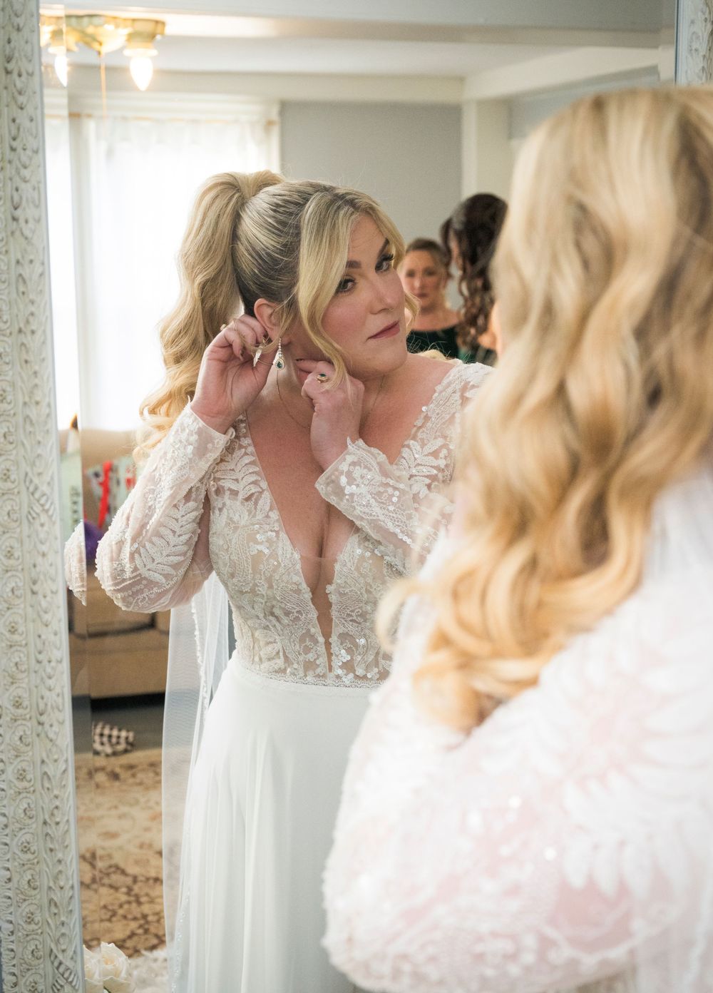 A close-up reflection in an ornate mirror shows final wedding preparations in a dressing room.